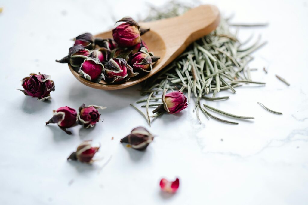 Close-up of dried roses and rosemary on a white background, perfect for herbal tea blends.